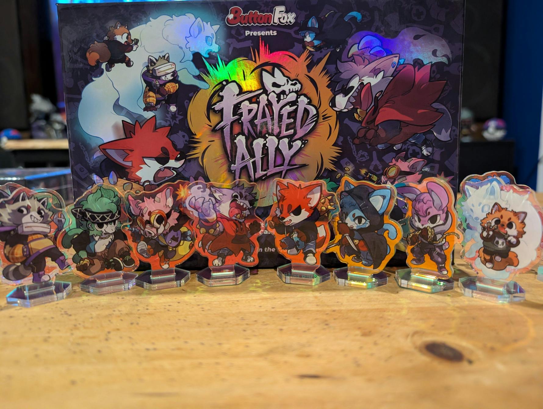 Frayed Ally board game box and a row of colorful anthropomorphic animal character acrylic standees