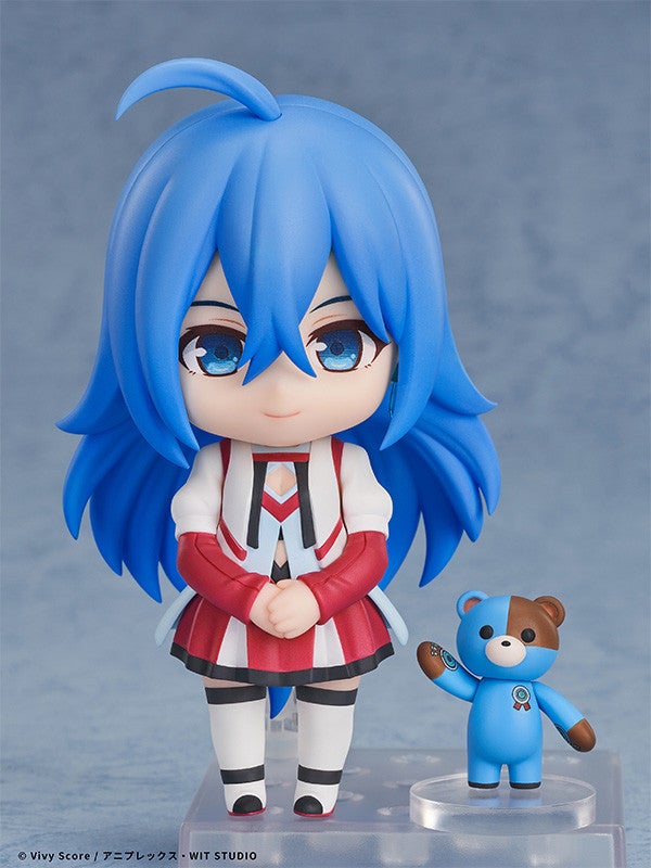 Blue-haired anime figure in white and red jacket and skirt standing next to a small blue and brown teddy bear