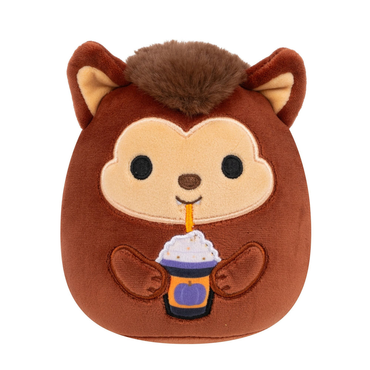 A brown Bigfoot Squishmallow plush toy with fuzzy brown hair and ears holds a Halloween-themed drink with whipped cream and a straw