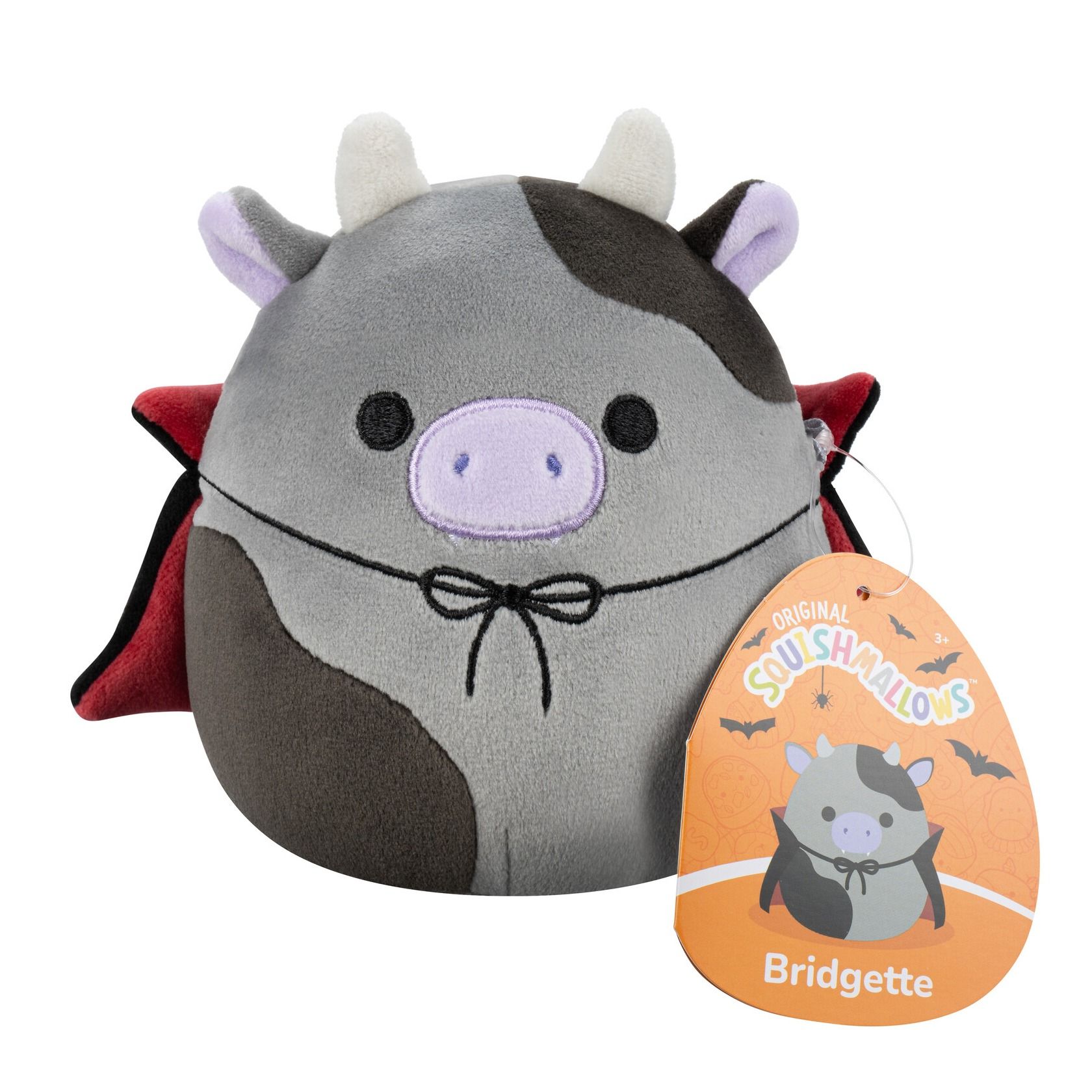 A gray and brown plush cow with white horns, purple snout, black eyes, wearing a black vampire cape with red lining and a black bow tie