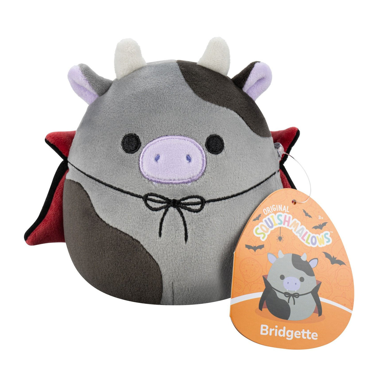 A gray and brown plush cow with white horns, purple snout, black eyes, wearing a black vampire cape with red lining and a black bow tie