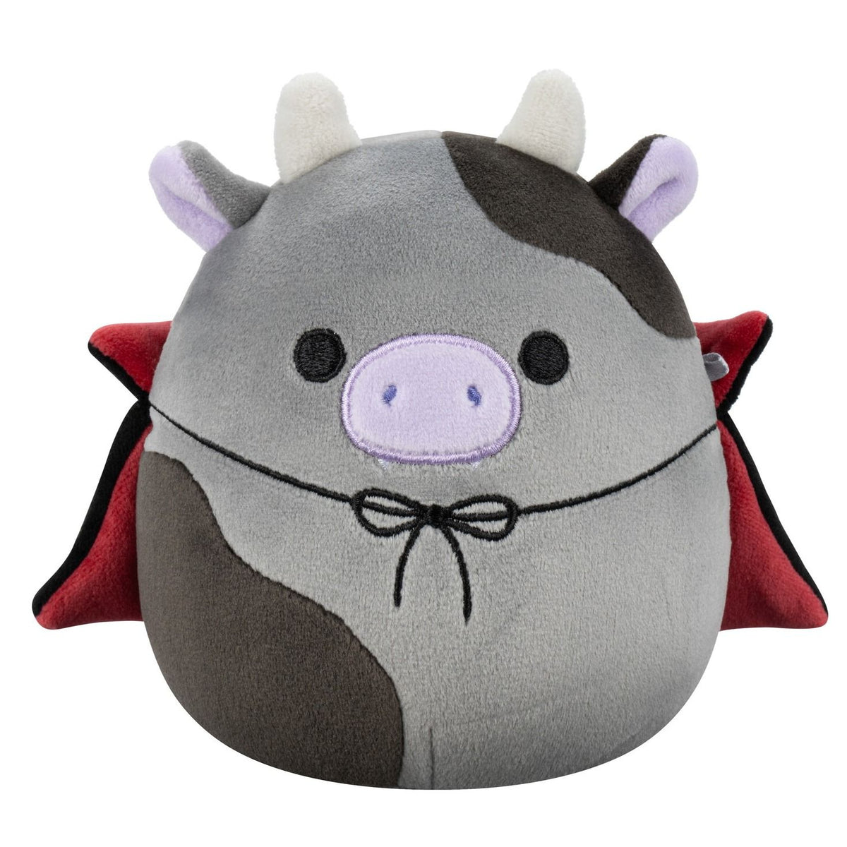 A round gray and black patched Squishmallow cow plush with white horns, a lavender snout, and a red and black cape tied with a bow