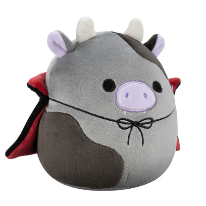 A gray and brown Squishmallow cow plush dressed as a vampire, wearing a red cape and showing tiny fangs