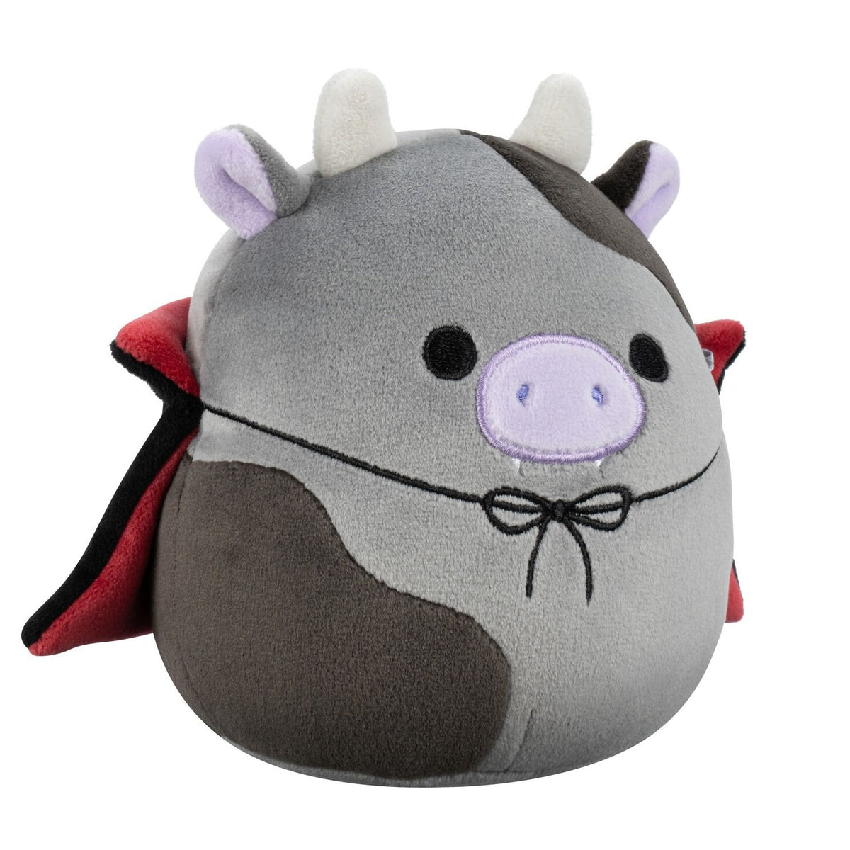 A gray and brown Squishmallow cow plush dressed as a vampire, wearing a red cape and showing tiny fangs