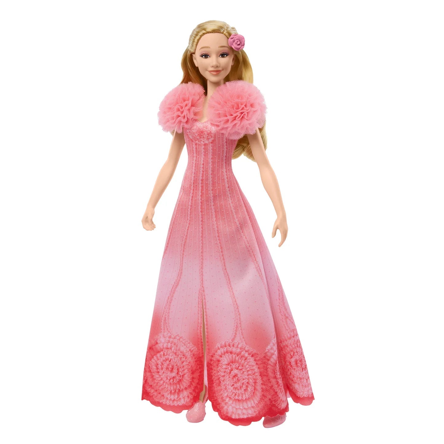 The Disney Wicked Singing Glinda doll stands against a white background, wearing a pink ombré gown with a fluffy tulle collar, long blonde hair, a pink rose, and patterned skirt hem