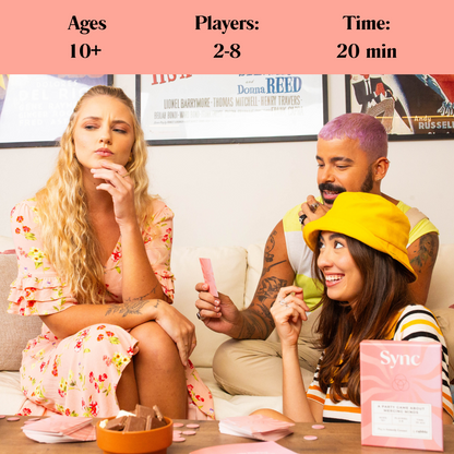 Three people playing the Sync card game on a white couch with pink cards and the Sync game box on a table