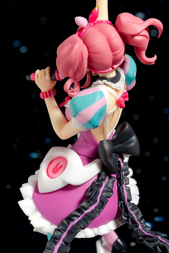 Pink haired anime figure in a purple dress singing into a microphone