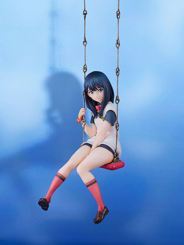 Anime figure of a girl with dark blue hair and light skin wearing a white and dark blue school uniform sitting on a red swing