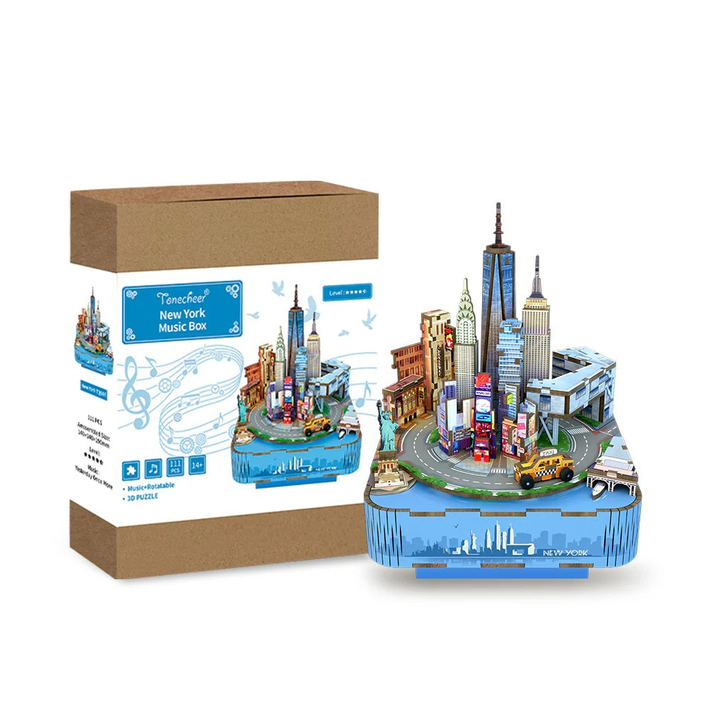Assembled 3D puzzle music box featuring the New York City skyline and landmarks, shown beside its brown cardboard box