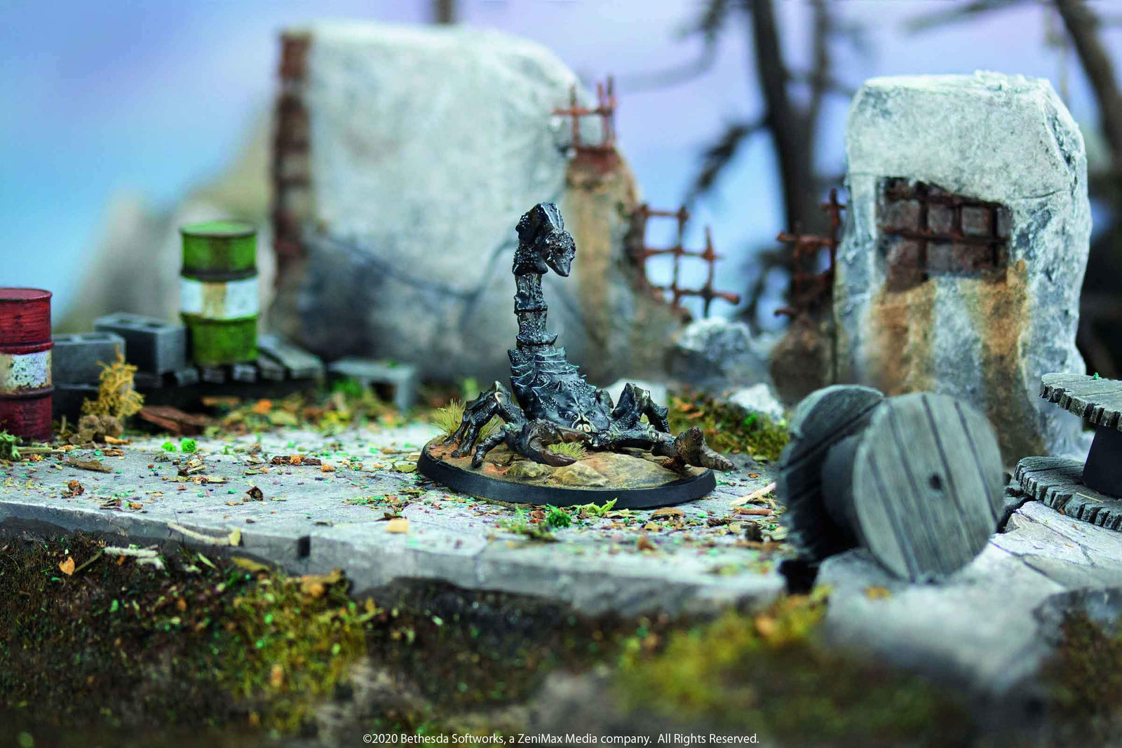 A dark miniature scorpion, tail raised aggressively, amidst ruined concrete, barrels, and debris.