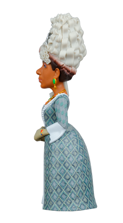 Side view of a MINIX Bridgerton Queen Charlotte Figure with dark skin, a tall white wig, green earrings, a gold necklace, and a patterned blue and green dress