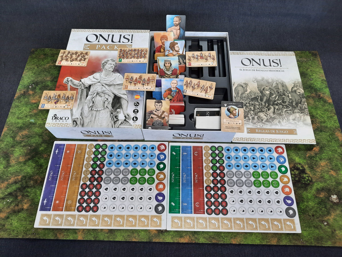 Onus!: Pack game box and components laid out on a table, including multiple unit cards with illustrations of ancient warriors, a rulebook, and dice, set up as if ready for play