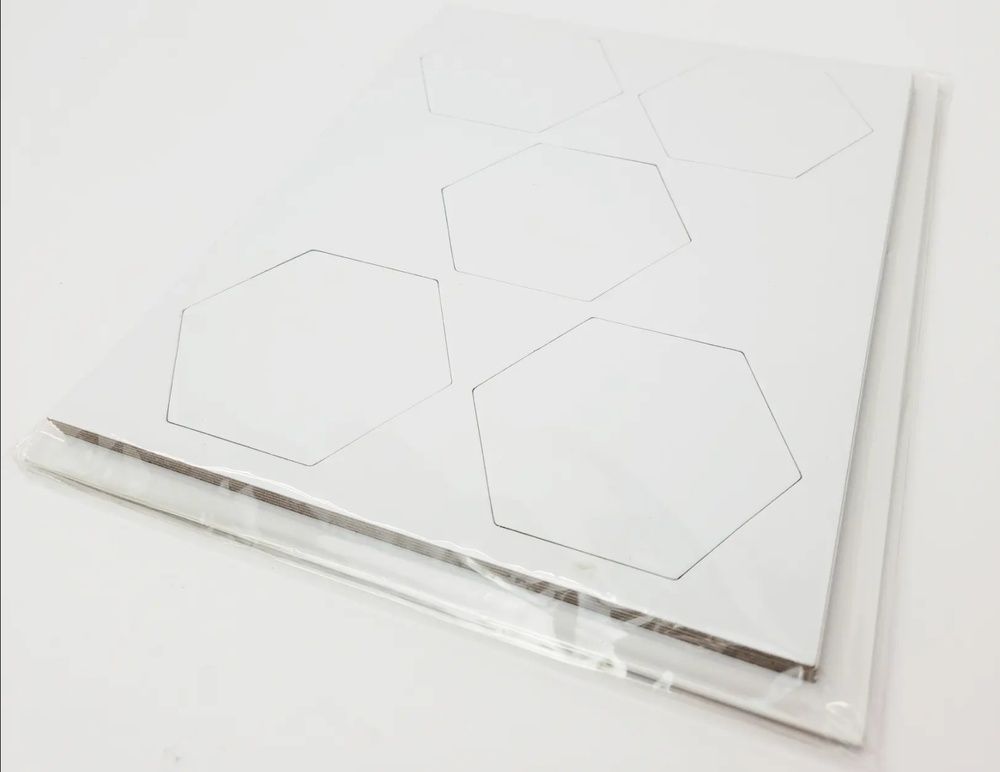 Stack of white hexagon paper cards with visible black outlines packaged in clear plastic wrap