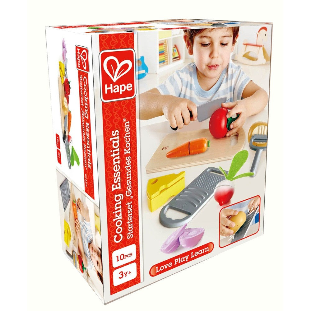 Hape 'Cooking Essentials' toy box, showing a young boy pretending to cut a toy tomato with a knife.