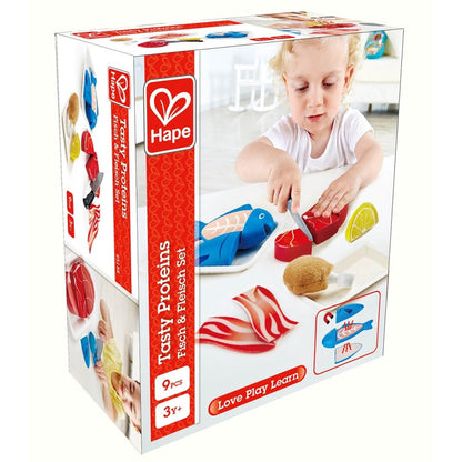 Product box for Hape's "Tasty Proteins" play food. A child cuts toy steak with a knife; toy fish, chicken, bacon on table.