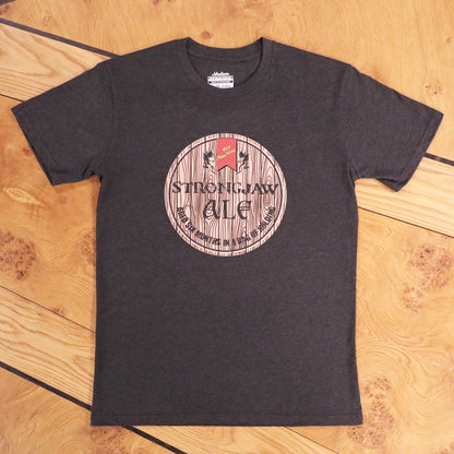 Dark grey t-shirt with a 'Strongjaw Ale' barrel label graphic including 'Vox Machina' logo, on wood