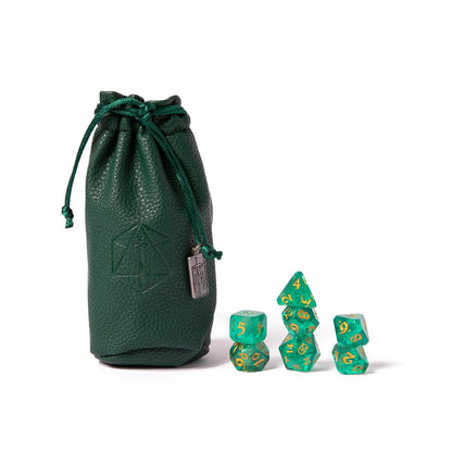 A dark green leather drawstring bag sits next to a stack of translucent green and gold polyhedral dice