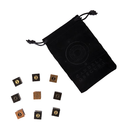 Black velvet Candela Obscura Premium Dice bag and 8 scattered square black/bronze dice with 1, 2, 3 and symbols