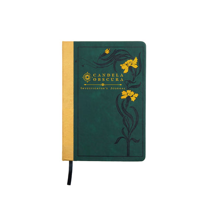 A dark green "Candela Obscura Investigator's Journal" with a gold spine, yellow floral art, and a black ribbon bookmark