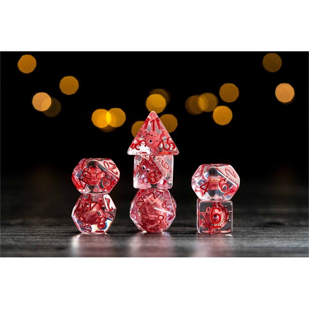 Three stacks of clear polyhedral dice with red inclusions, set on a dark surface with golden bokeh lights