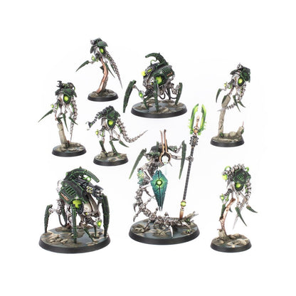 Set of seven Necron miniatures, silver and dark green robotic warriors with glowing green eyes and energy, including Skorpekh Destroyers and a Cryptek model