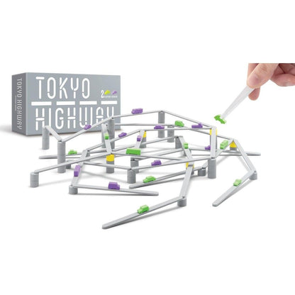 Hand placing a road piece onto the multi-layered structure of the Tokyo Highway board game