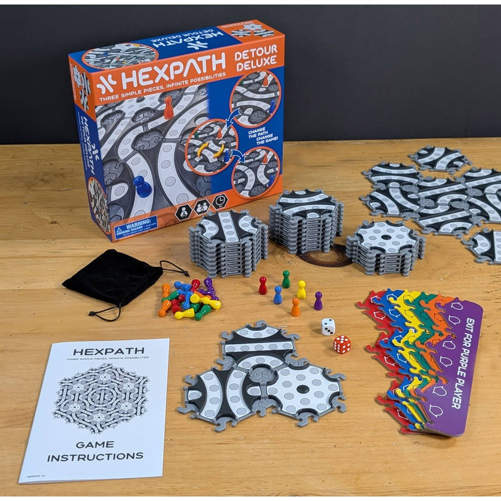 Hexpath Detour Deluxe board game components displayed: box, stacked path tiles, colored pawns, dice, and instructions