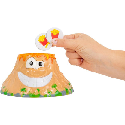 Close-up of the cartoon volcano game base with a wide smile as a person places two french fry tokens into the lava opening