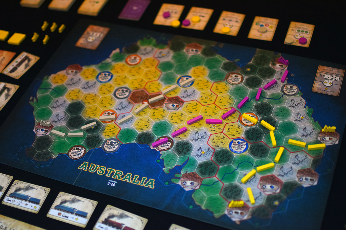 Detailed Australia train board game with yellow, pink, white tracks, city tokens, and cards