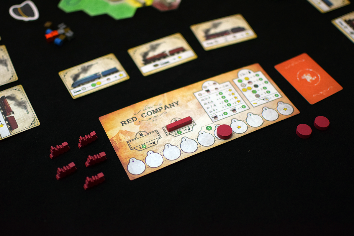 Board game: "Small Railroad Empires: Red Company" player mat with red tokens and train engine cards on a black table