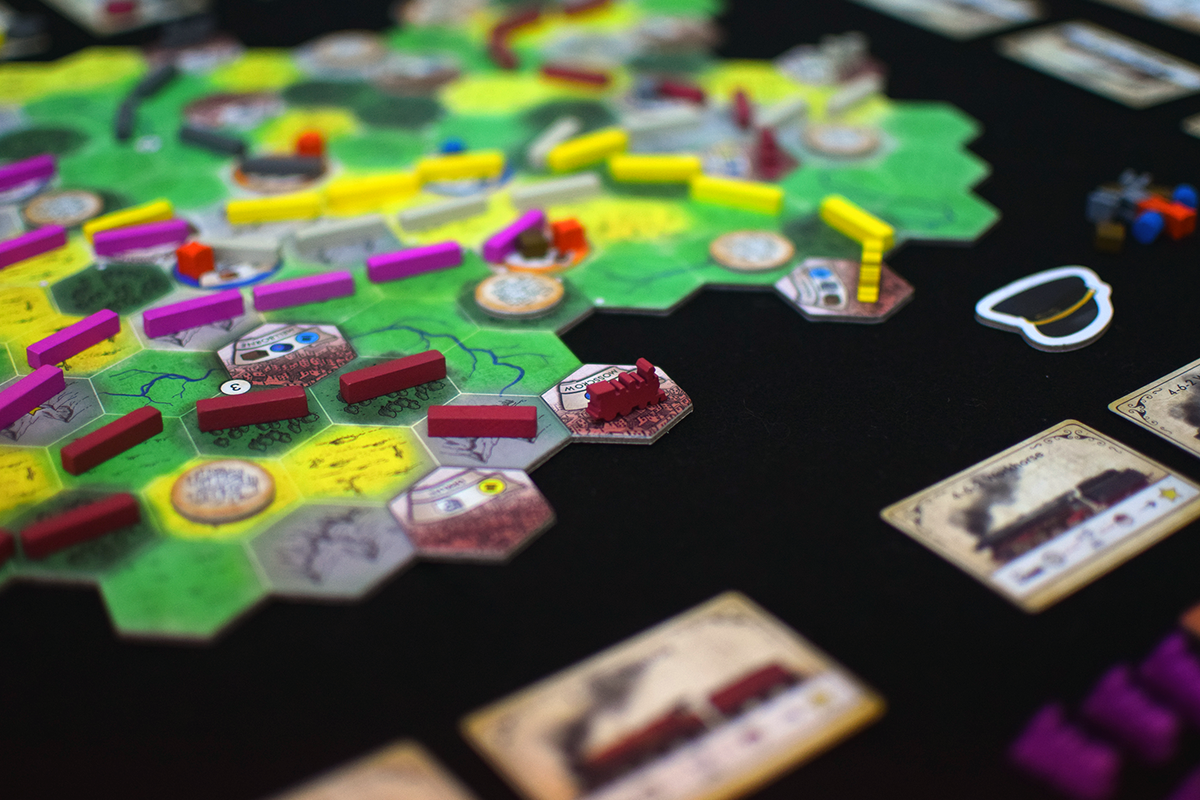 Train board game in progress: hexagonal map tiles, red train on "Moscow", colorful pieces, and train cards