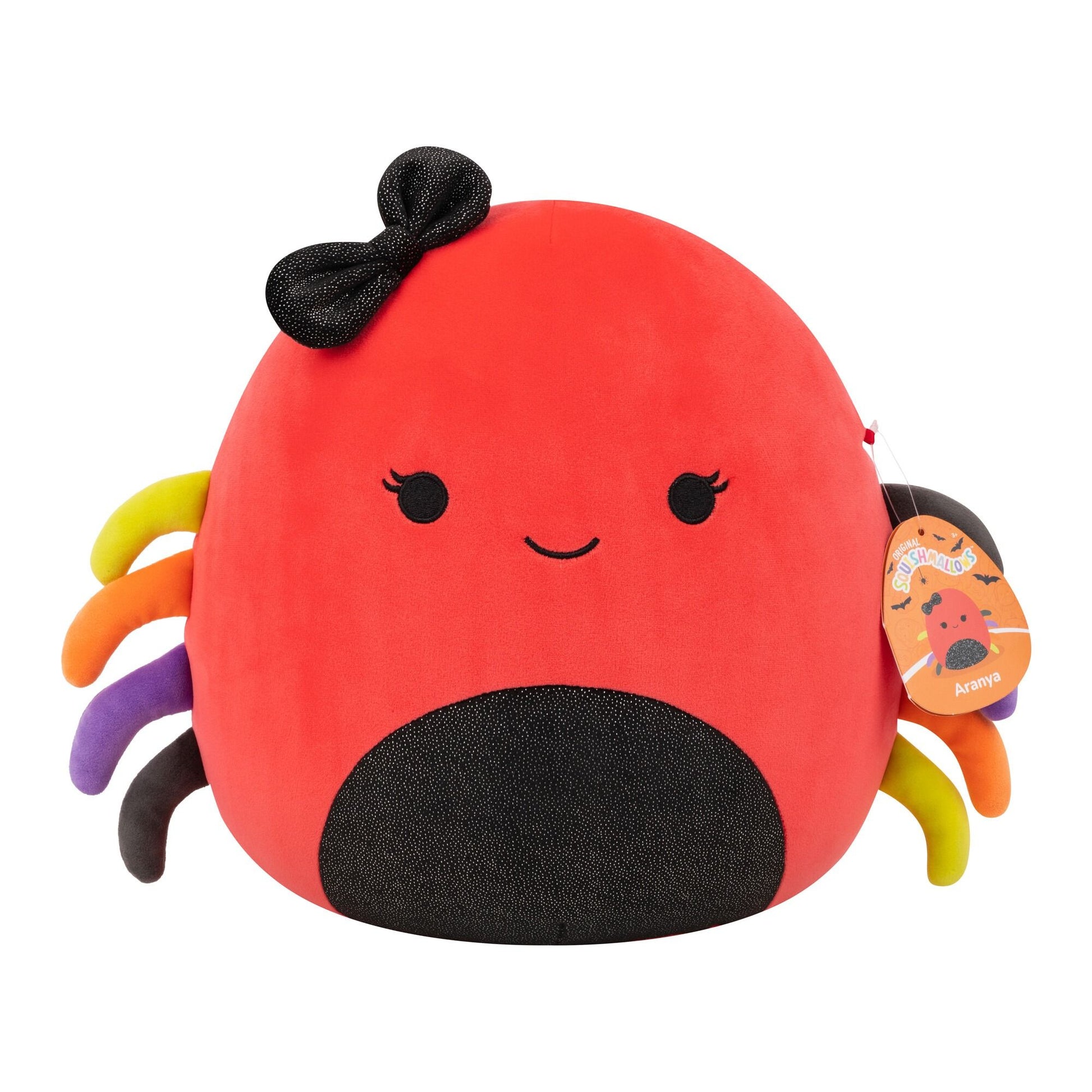 A red Squishmallow spider plush with a black bow, speckled belly, smiling face, and colorful yellow, orange, purple, and black legs