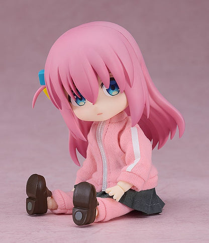 Cute anime figure with long pink hair and blue eyes wearing a pink tracksuit and grey skirt sitting down