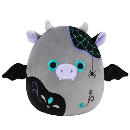 A gray Squishmallow cow with bat wings, horns, fangs, floral eyes, a spiderweb, and a hanging spider