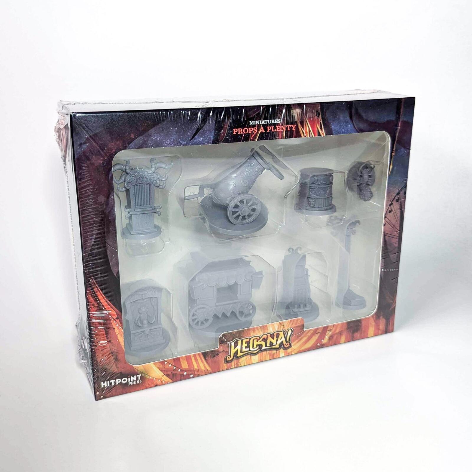 A shrink-wrapped box of 'Heckna! Props A Plenty' tabletop miniatures, displaying various unpainted grey props.