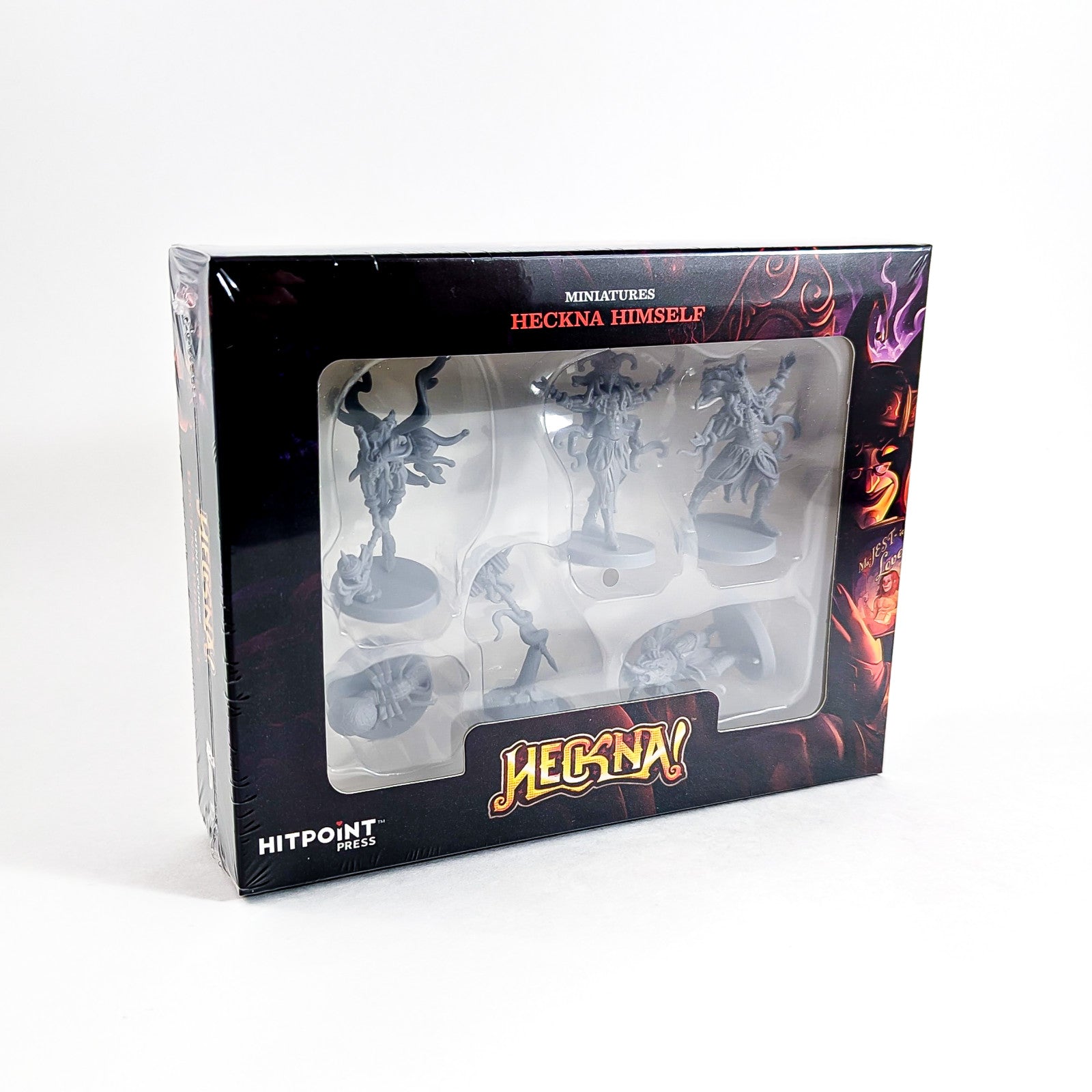 Box of "HECKNA HIMSELF" miniatures, showing six unpainted grey fantasy figures through a clear window.