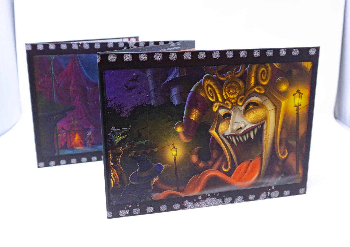 Open game booklet: Ornate gold and purple jester mask with sharp teeth and tongue in a spooky carnival scene, filmstrip border.