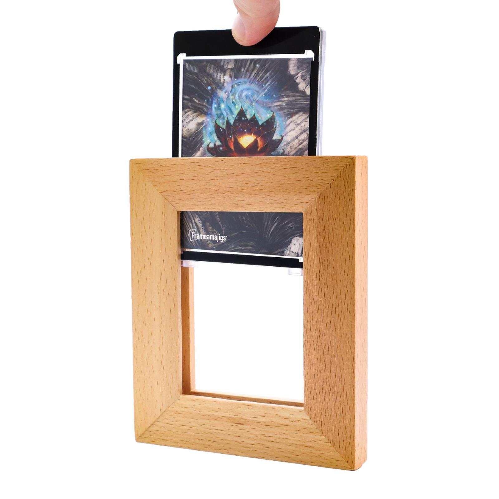 Hand inserting a glowing lotus card into a wooden Frameamajigs display frame