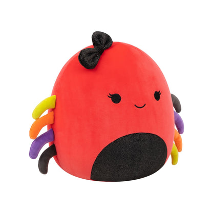 A red Squishmallow plush with a black glitter bow, embroidered eyes and smile, a black speckled belly, and multicolored legs
