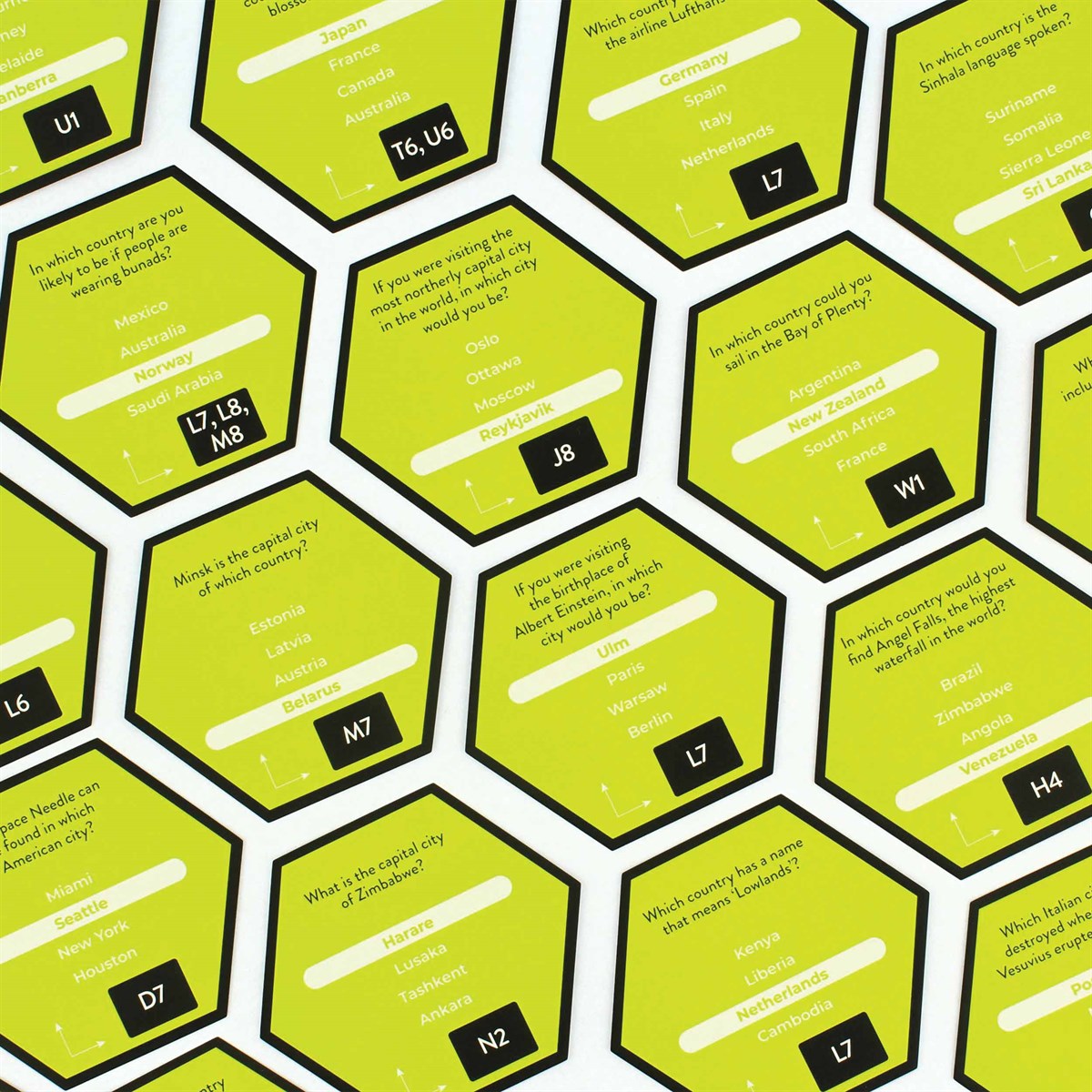 Overhead view of hexagonal lime-green game tiles showing trivia questions, multiple-choice answers, and reference codes