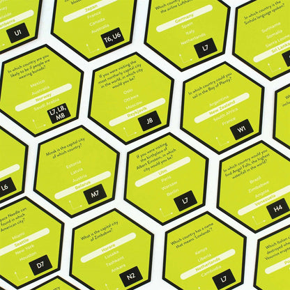 Overhead view of hexagonal lime-green game tiles showing trivia questions, multiple-choice answers, and reference codes
