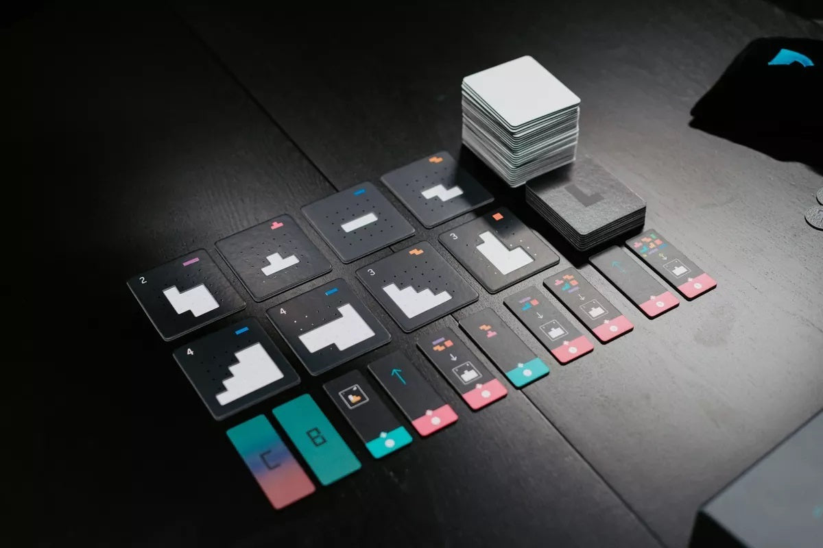 Various dark-colored cards and game pieces arranged on a dark wooden surface