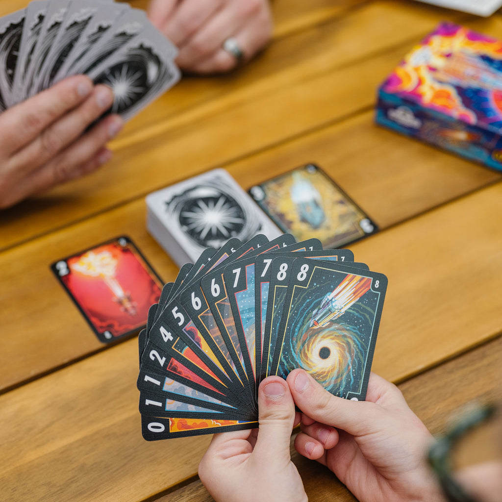 Board game of 3-2-1 Countdown card game in play featuring colourful numbered cards from 0-8 in hand and a draw pile on a wooden table