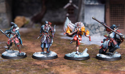 Four detailed Japanese-inspired fantasy miniatures, including a fire-wielder and a polearm warrior, stand on snowy bases