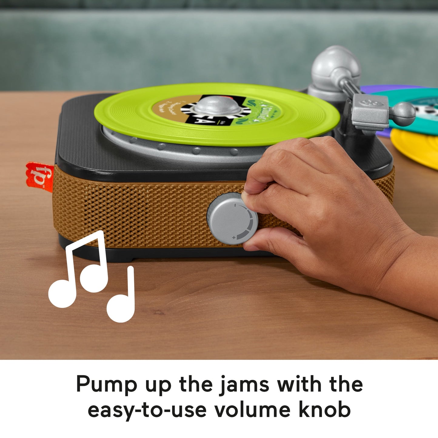 Child's hand adjusts the volume knob on a toy record player with a lime green record