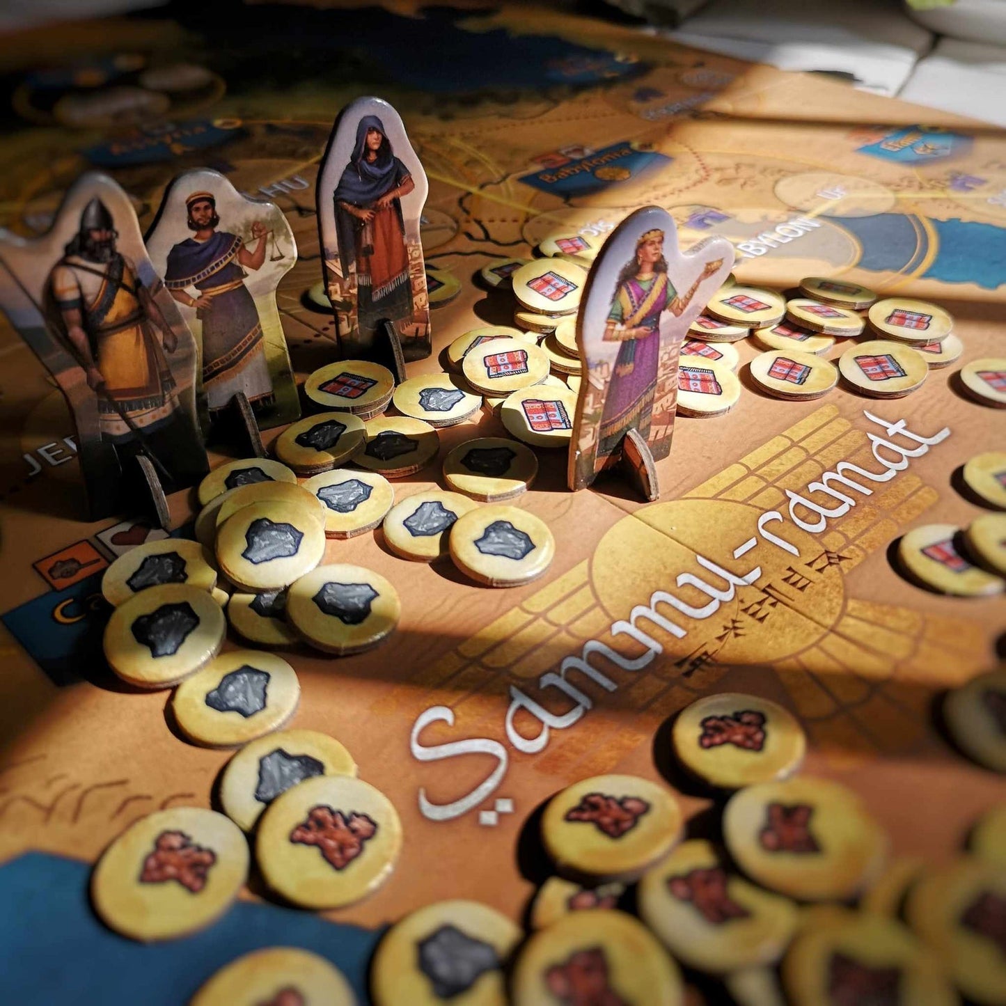 Historical board game with four player standees depicting ancient figures and various circular tokens on a map