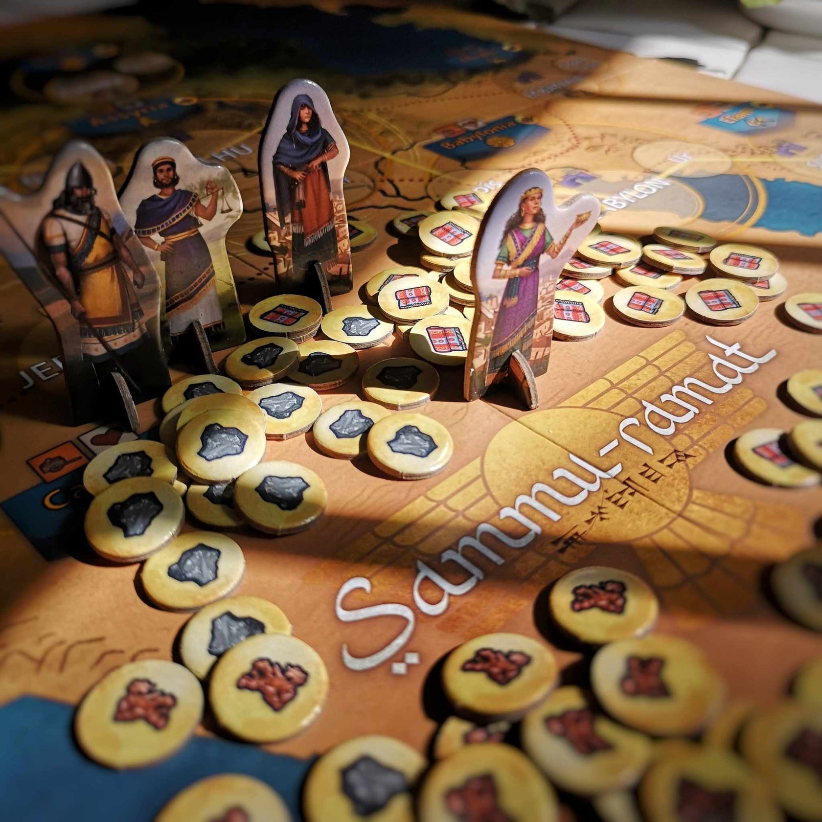 Historical board game with four player standees depicting ancient figures and various circular tokens on a map