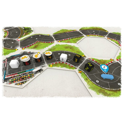 Rallyman GT board game setup showing modular race track tiles, dice, a blue car token, and other game pieces with a grandstand near the start