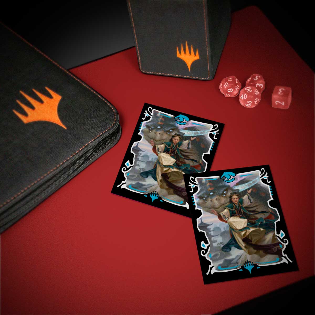 Two Magic: The Gathering cards showing a rider on a beast, plus a binder, deck box, and dice on a red mat