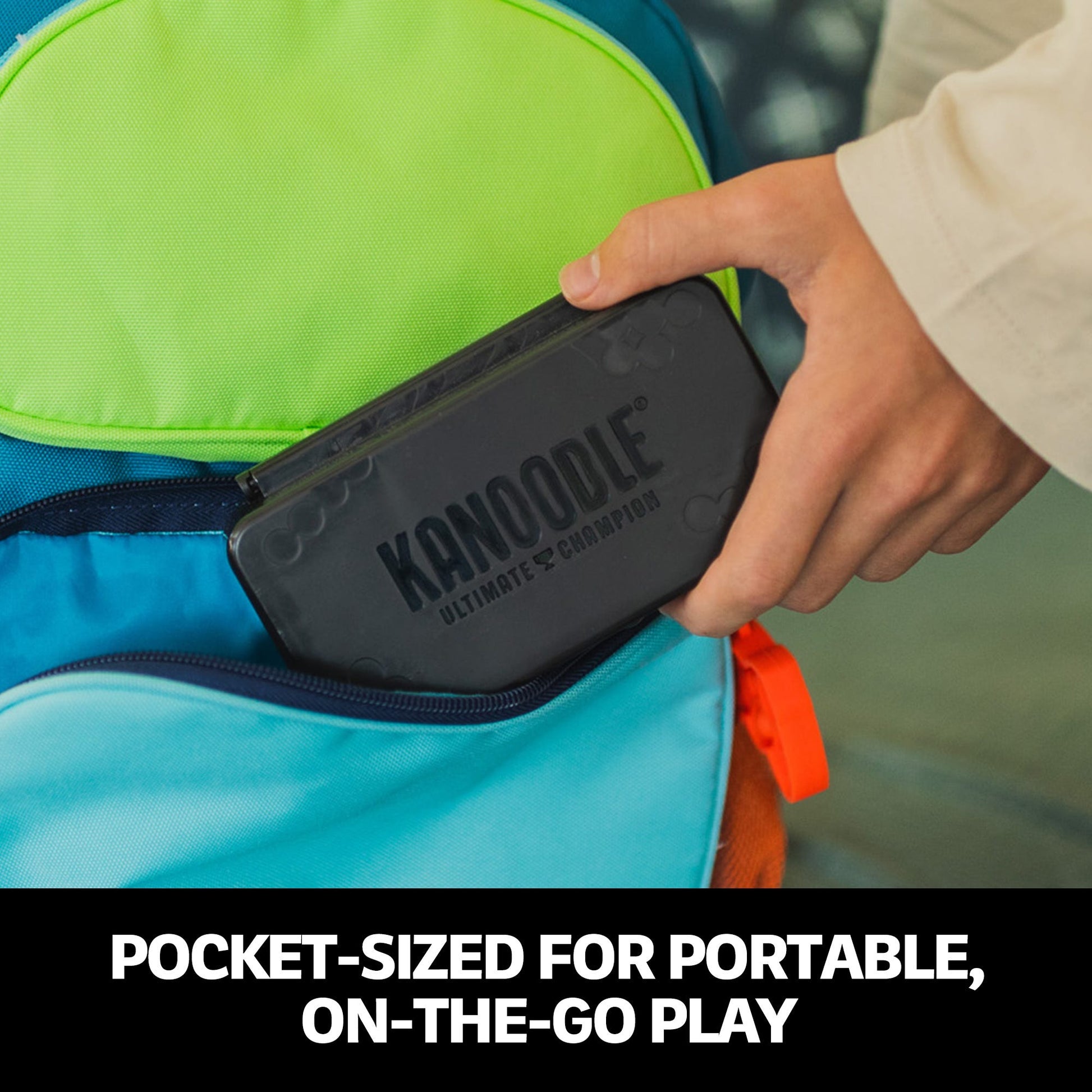 Hand inserting a grey Kanoodle Ultimate Champion game case into a colourful backpack for portable play